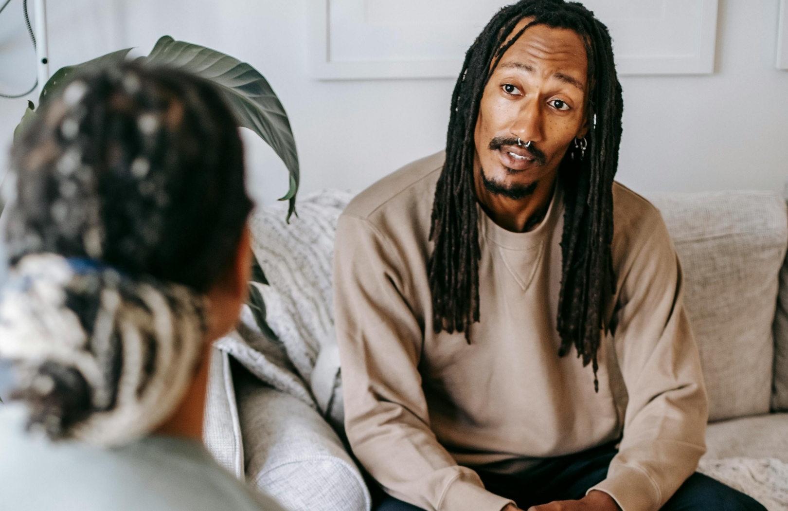 Mann mit Dreadlocks im Gespräch, sitzt auf einem Sofa